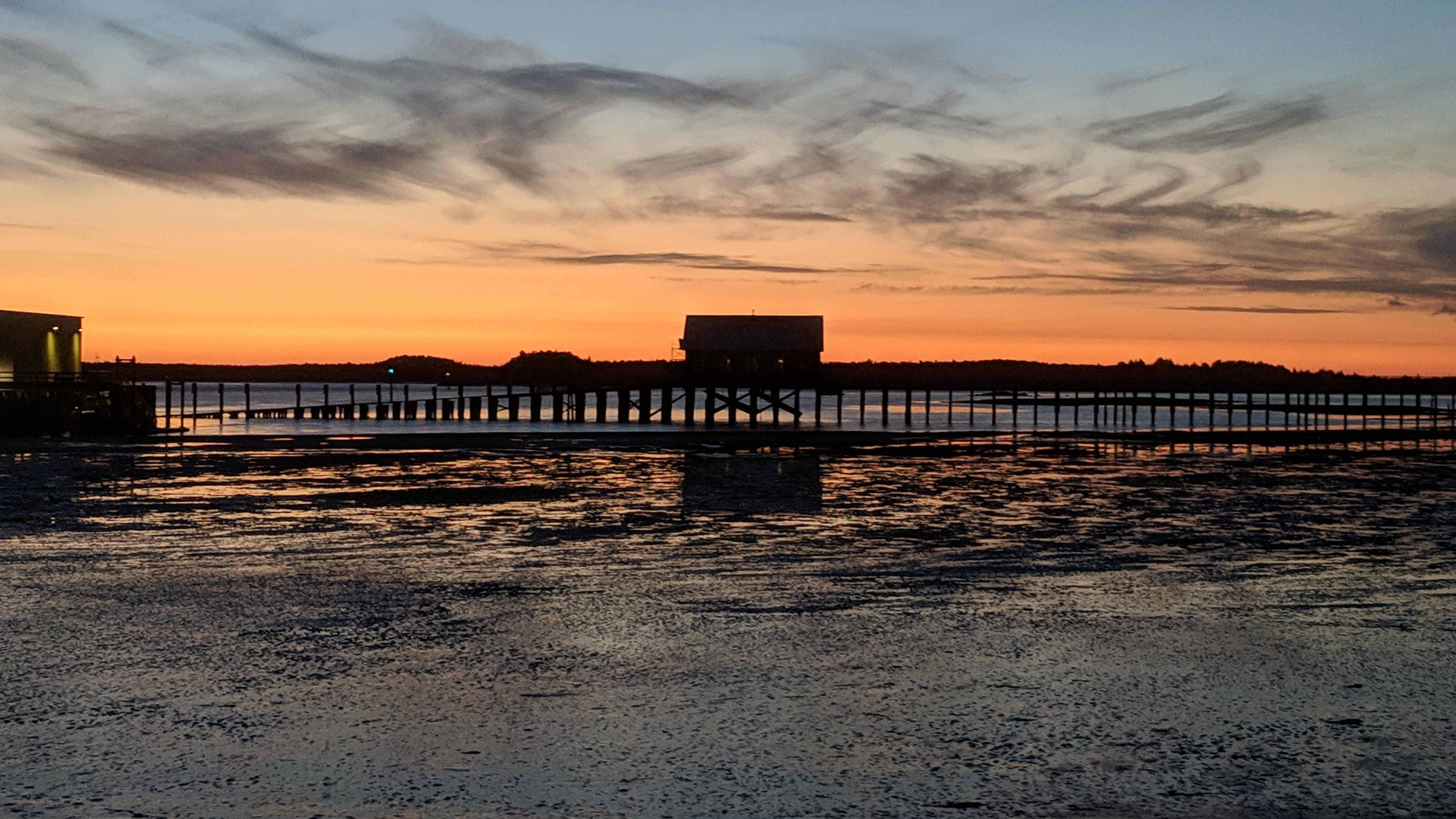 Old Coast Guard Boathouse Tillamook Bay at sundown. The Pacific Ocean is behind that treeline back there.